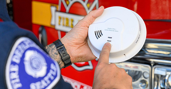 A firefighter tests a smoke alarm